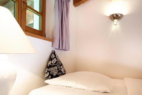 Zimmer mit einem Bett, einer Lampe und einem Fenster in der Unterkunft Kaffeehaus Kranzbach in Krün