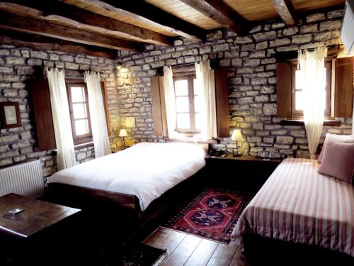a bedroom with two beds and a table and windows at Arhontiko Aristis in Aristi