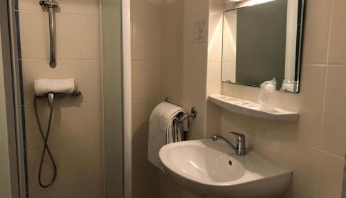 uma casa de banho com um lavatório e um chuveiro com um espelho. em Hôtel-Bar l'Embarcadère em La Malène