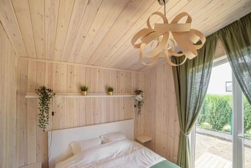 Schlafzimmer mit einem Bett und einer Decke mit einem Fenster in der Unterkunft EPA Brīvdienu mājiņa in Carnikava