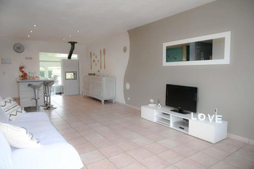 un salon avec un canapé blanc et une télévision dans l'établissement La Maison Maluti - avec Baby-foot, Billard & Wifi, à Hostens