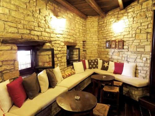 a room with a stone wall with a couch and tables at Arhontiko Aristis in Aristi