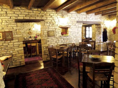 a dining room with tables and chairs and a stone wall at Arhontiko Aristis in Aristi