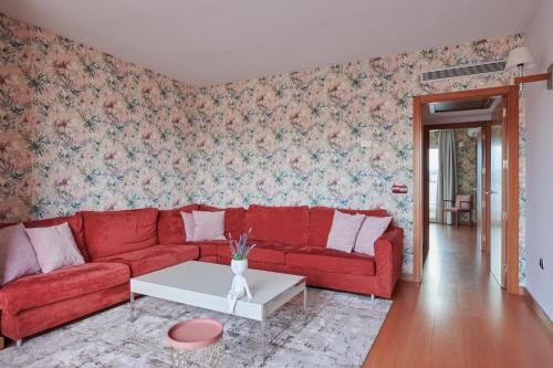 a living room with a red couch and floral wallpaper at Ramblas Vendrell in El Vendrell