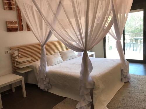 a bedroom with a white bed with curtains at Villa con piscina privada in Olivella