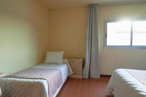 a small bedroom with two beds and a window at Ramblas Vendrell in El Vendrell