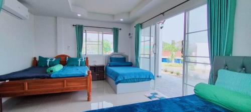 a bedroom with two beds and a large window at Poonsap Homestay in Nan