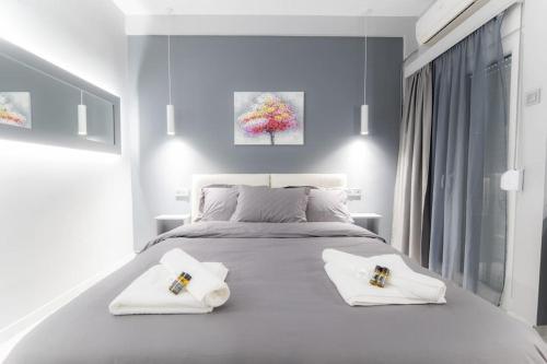 a white bedroom with a large white bed with two towels at Lux seaside apartment by Volos hospitality in Volos