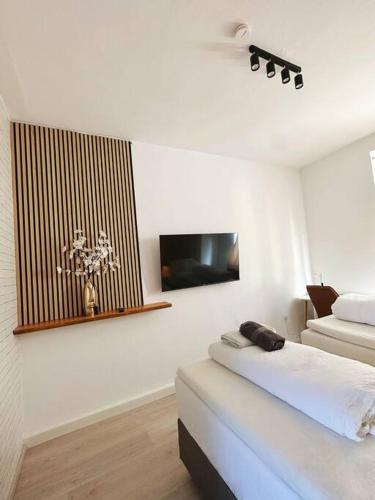 a white room with a bed and a flat screen tv at 2 Schlafenzimmer 5 Betten in Duisburg