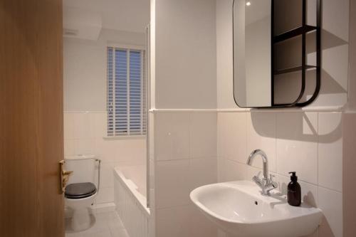 a white bathroom with a sink and a toilet at Stunning 2 bed flat with parking, and garden with mountain views in Crieff