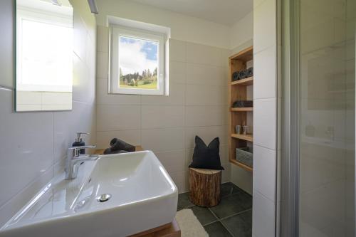 a white bathroom with a sink and a window at Ferienappartements Schrattengut in Abtenau