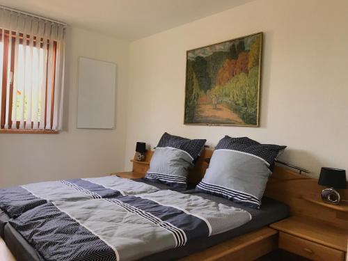 a bed with two pillows and a painting on the wall at Haus Fjord in Am See