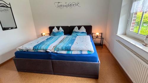 a bedroom with a bed with blue sheets and a window at Ferienwohnung Margrit in Detern