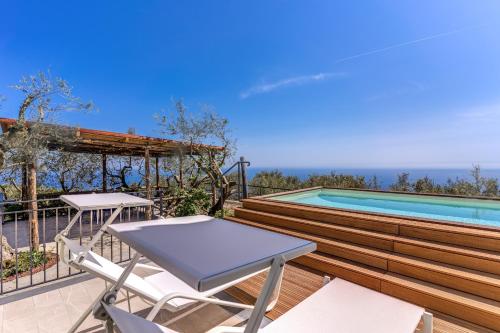 a table and chairs on a deck next to a swimming pool at Villa Rusinella Minimalist Retreat with Sea Views by Feeling Italy in Massa Lubrense