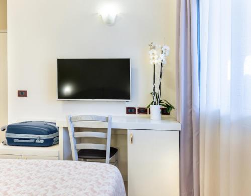 a room with a bed and a desk with a television at Hotel Fenice Gluten Free in Milano Marittima