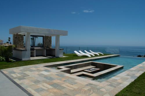 a pool with white chairs and a gazebo at Benalmadena Stupa luxury Villa in Benalmádena