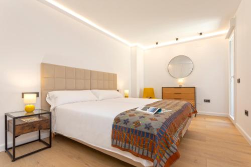 a bedroom with a large white bed and a table at Malagueta Luz by Renthas in Málaga