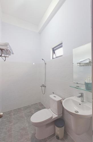 a white bathroom with a toilet and a sink at KHÁCH SẠN VĂN KHANG in Bạc Liêu