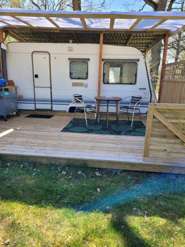 a rv with a table and chairs on a deck at Blankaholm Adria husvagn in Blankaholm