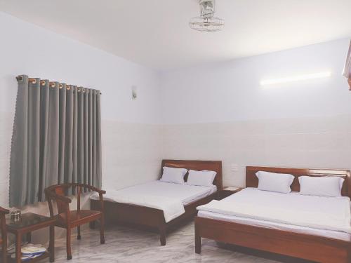 a room with two beds and a chair at KHÁCH SẠN VĂN KHANG in Bạc Liêu