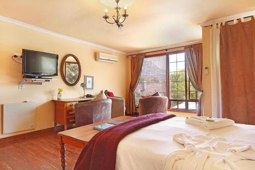 a bedroom with a bed and a desk and a tv at Harfield Guest Villa in Cape Town