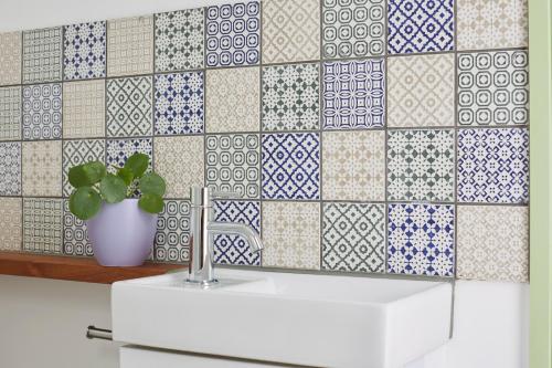 a bathroom with a white sink and a tile wall at Puckaster Cove Cabin in Niton