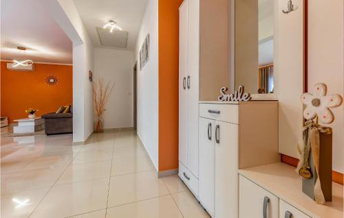 a kitchen with orange walls and white cabinets at Cozy Home In Skatari With Outdoor Swimming Pool in Šikići
