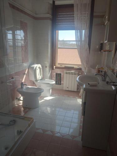 baño con 2 aseos, lavamanos y ventana en Casa Costantino en Campanedda