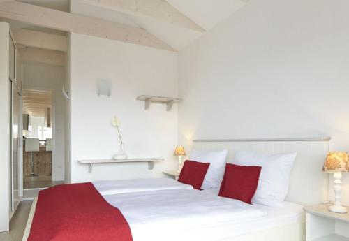 Schlafzimmer mit einem weißen Bett und roten Kissen in der Unterkunft Sea Captain - Ferienwohnungen in Büsum