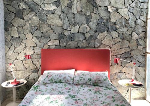 1 dormitorio con cama roja y pared de piedra en Jauja, en San Javier