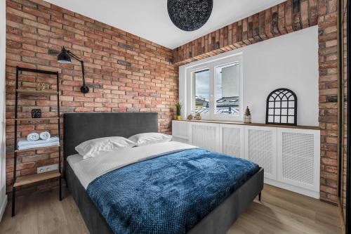 Un dormitorio con una pared de ladrillo y una cama en Vistula Loft Blue Apartment, en Varsovia