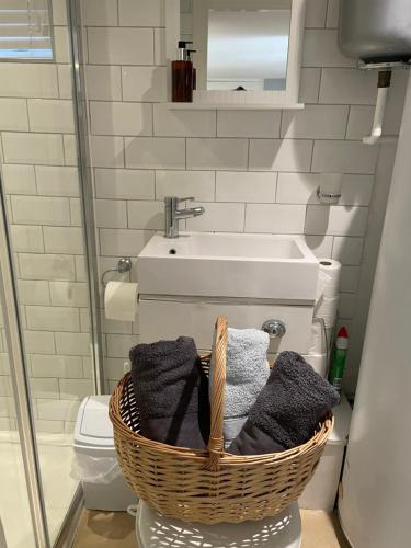a bathroom with a basket of towels and a sink at Imperial House Holiday Let in Herne Bay