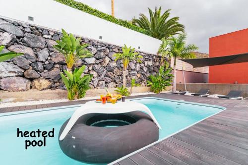 una piscina con un letto al centro di Villa Collection Madroñal - Heated Pool BBQ XBox ad Adeje