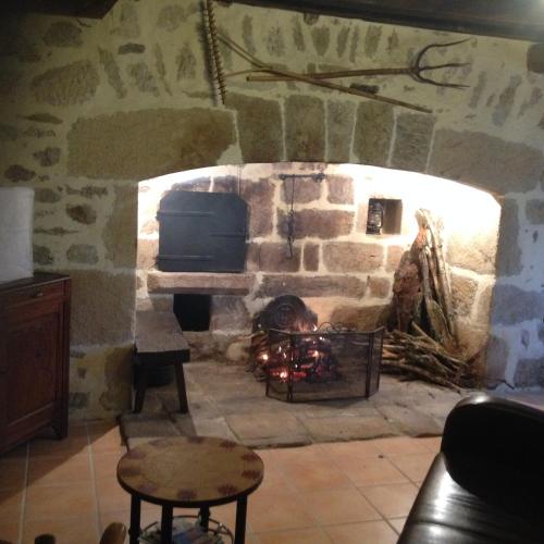 une cheminée en pierre avec une télévision et un foyer dans l'établissement Domaine de Nalou - Gîte, à Saint-Geniez-ô-Merle