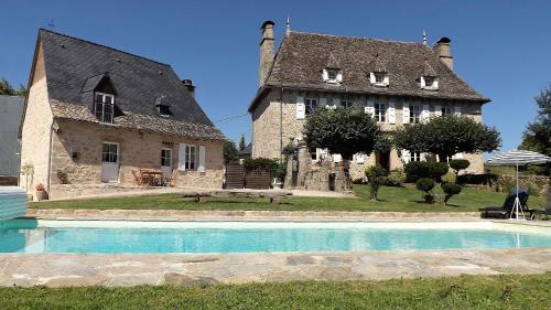 un grand bâtiment avec une piscine en face d'une maison dans l'établissement Domaine de Nalou - Gîte, à Saint-Geniez-ô-Merle