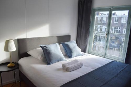 1 cama con almohadas azules y blancas y ventana en Private 4P top floor - hostel apartment en Ámsterdam