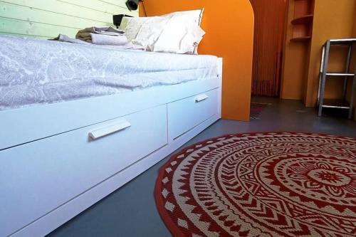 a bedroom with a white bed and a red rug at Private small studio in Costa de Caparica in Costa da Caparica