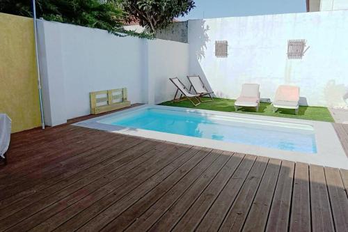 uma piscina com duas cadeiras ao lado de um deque de madeira em Private small studio in Costa de Caparica em Costa da Caparica