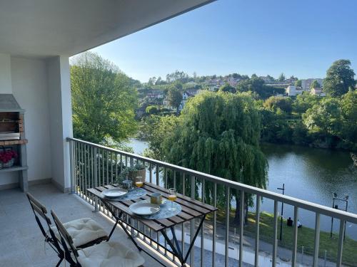 a balcony with a table and chairs and a river at PLACIDO RIVER HOUSE APARTAMENTO in Ponte da Barca