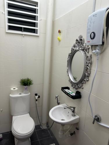 y baño con aseo, lavabo y espejo. en The Amore Homestay en Muar