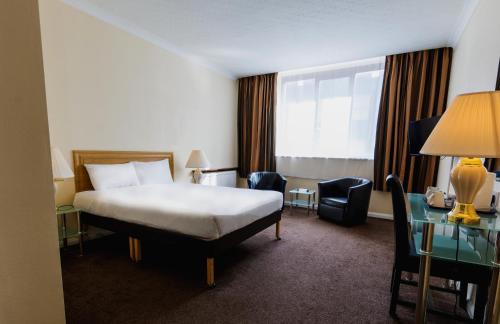 マンチェスターにあるブリタニア ホテル シティーセンター マンチェスターのベッドとガラスのテーブルが備わるホテルルームです。