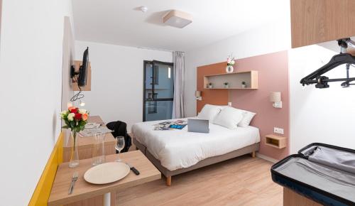 a bedroom with a bed and a table with a laptop on it at Apparthotel Le Hüb TOULON in Toulon