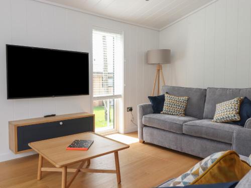a living room with a couch and a flat screen tv at Blackthorn Copse in Ulverston