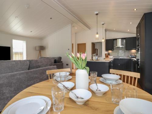a dining room table with white plates and flowers on it at Blackthorn Copse in Ulverston