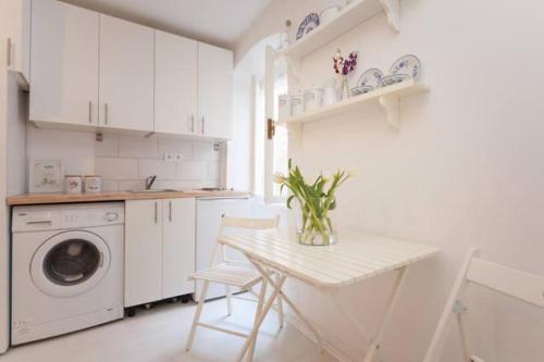 a white kitchen with a table and a washing machine at Vintage Apartment Rovinj Old Town in Rovinj