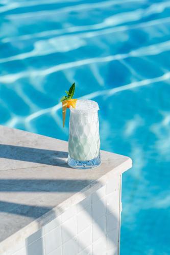 a drink sitting on a table next to a swimming pool at Liberty Hotels Lara in Lara