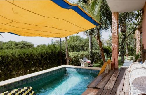a swimming pool with an umbrella and chairs and a swimming pool at Hajrienne guest house in Tangier