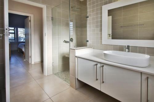 a white bathroom with a sink and a mirror at Shorebreak in Southbroom