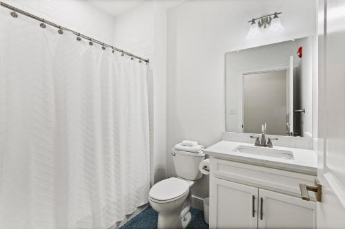 a white bathroom with a toilet and a sink at Oasis by Seaport Stays in Wildwood