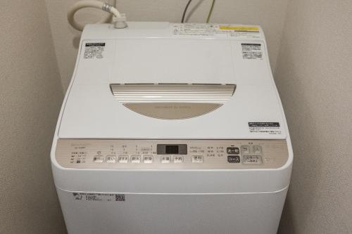 a washing machine is sitting in a room at Living Inn Asahibashiekimae Premier in Naha